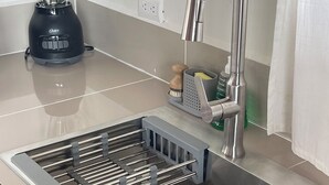 Eine Küche mit Spüle aus Edelstahl, einem integrierten Messerblock und einem Mixer auf der Arbeitsplatte.