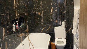 Een moderne badkamer met een vrijstaand bad, een toilet en een wastafel met lades.