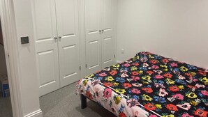 Een slaapkamer met een bed, witte dubbele deuren en een vloerbedekking.