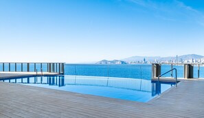 Une piscine dotée d’une terrasse en bois et offrant une vue sur le paysage urbain en arrière-plan.