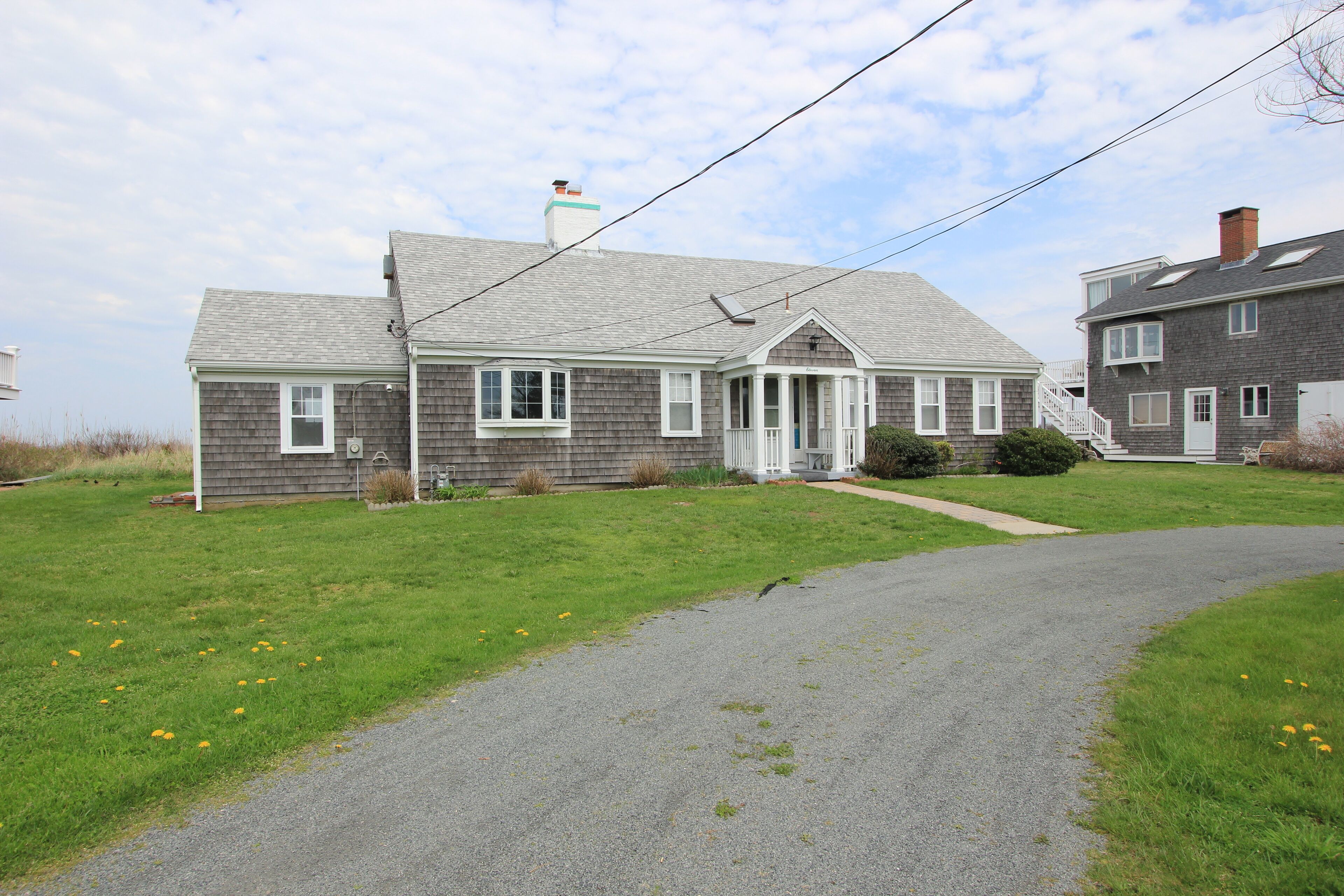 A two-story house with a front porch, a driveway, and a grassy yard.