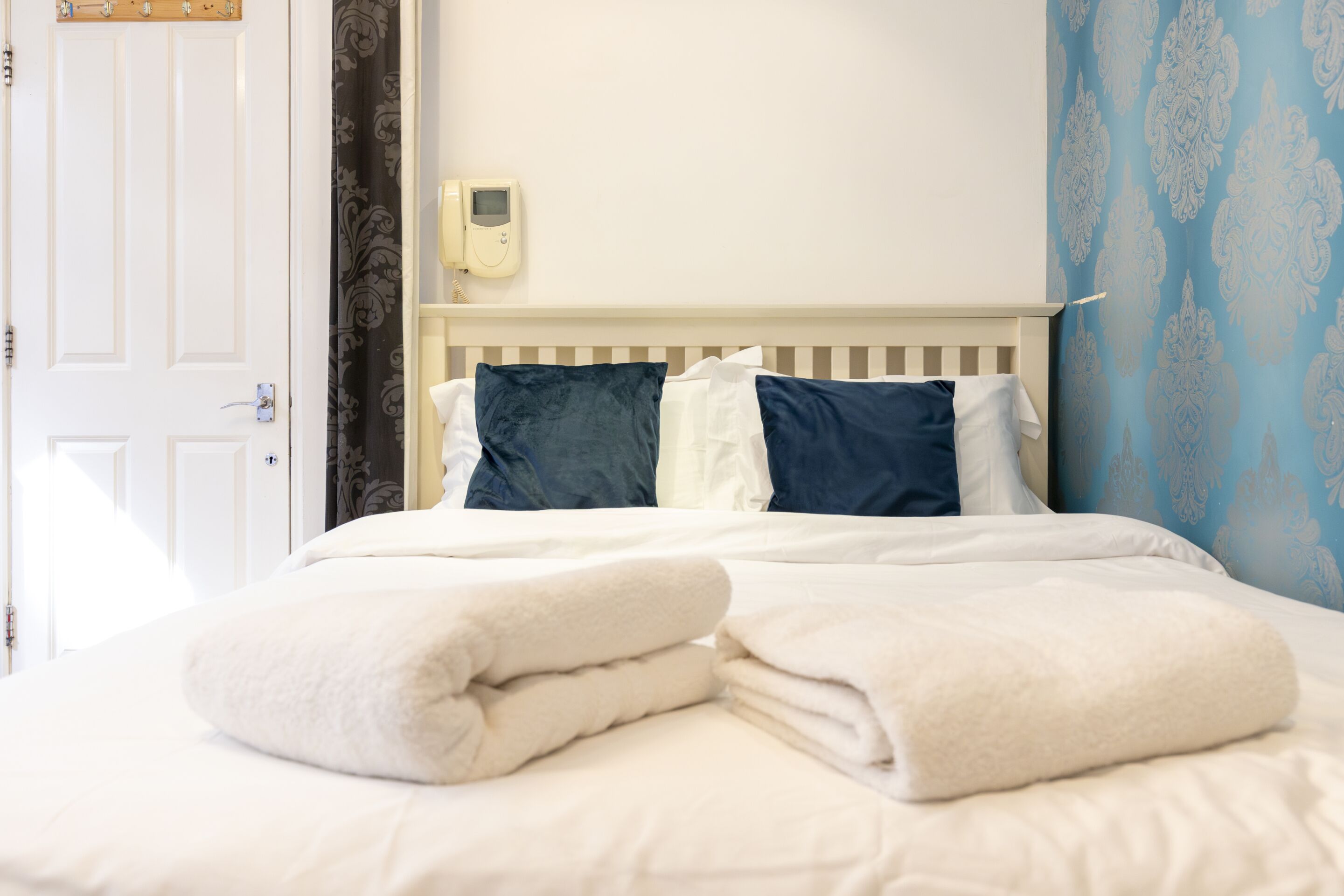 Ein Hotelzimmer mit einem Bett, einem Nachttischtelefon und einer Tür.