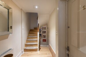 Un estrecho pasillo con una escalera de madera que lleva a una plataforma.