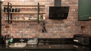 Una cucina moderna con rivestimento in mattoni, elettrodomestici in acciaio inossidabile e mensole aperte con utensili da cucina.