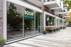 Ein modernes Gebäude mit Glasfassade und dem Schriftzug "BOOM BATTLE BAR" im Fenster.