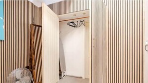 Una stanza con un divisorio in listelli di legno, una sedia e un appendiabiti.