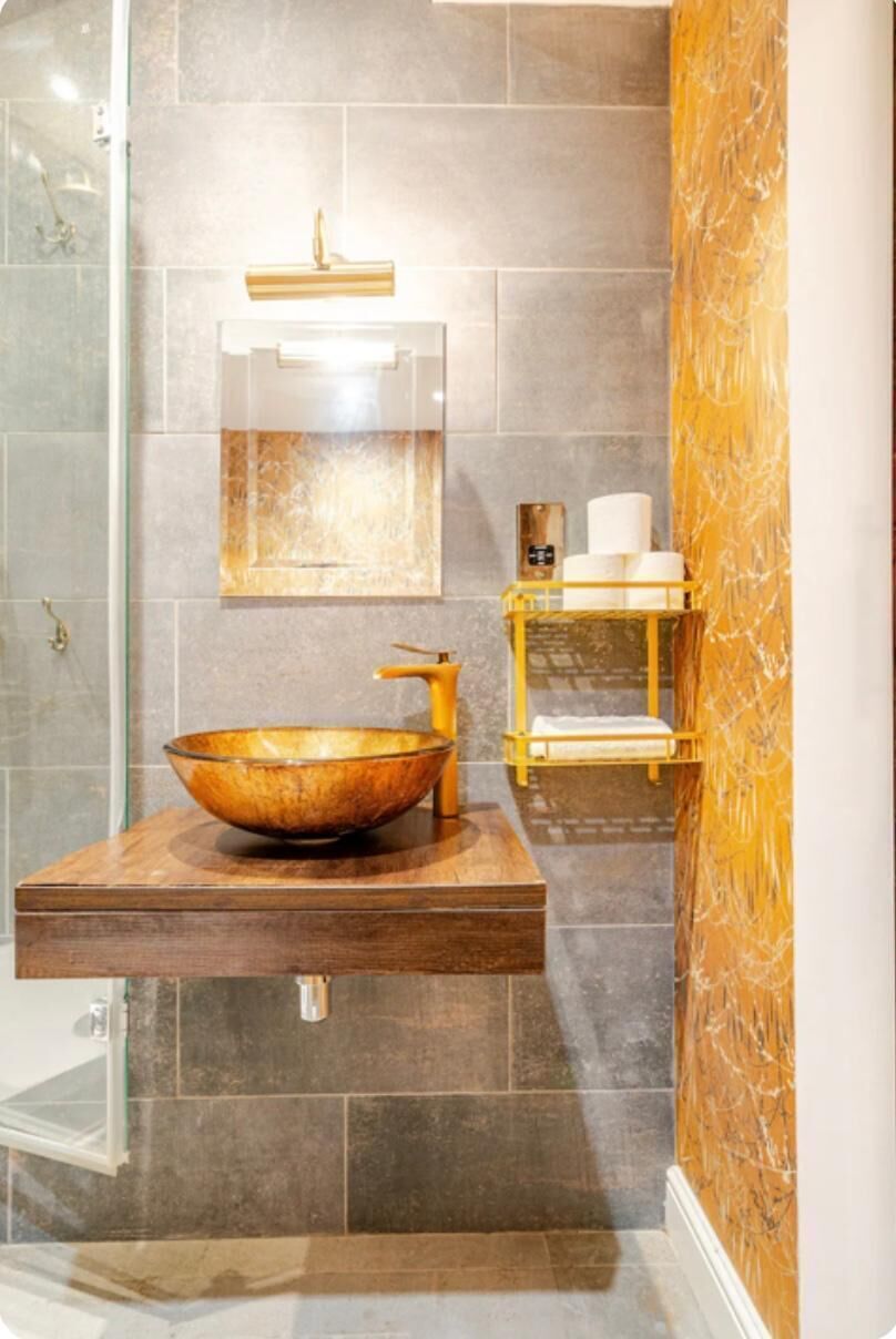 A bathroom with a large vessel sink, a mirror, and a towel rack.