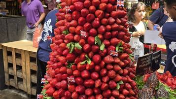 A display of strawberries arranged in a pyramid shape with small flags, surrounded by baskets and a sign indicating a price of £9.50.