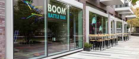 Un bâtiment moderne avec une façade en verre et l’inscription « BOOM BATTLE BAR » sur la vitrine.