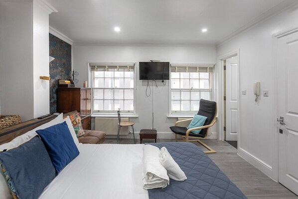A bedroom with a bed, a chair, a desk, and a TV.
