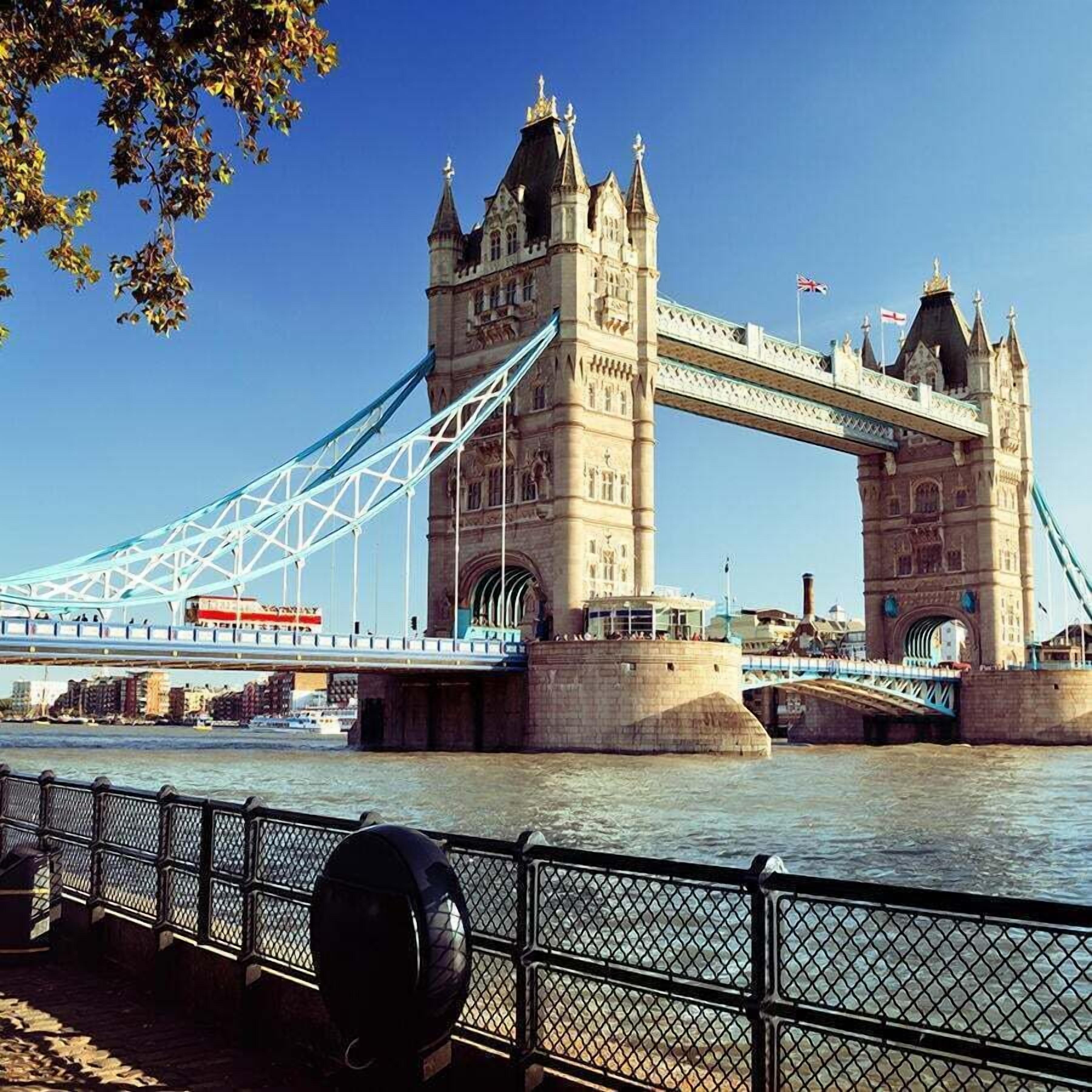 A historic stone bridge with two towers and a suspension cable, spanning a river.
