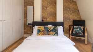 A bedroom with a bed, a chair, and a wardrobe. - Aldgate London City Charming Studio 5 (London)