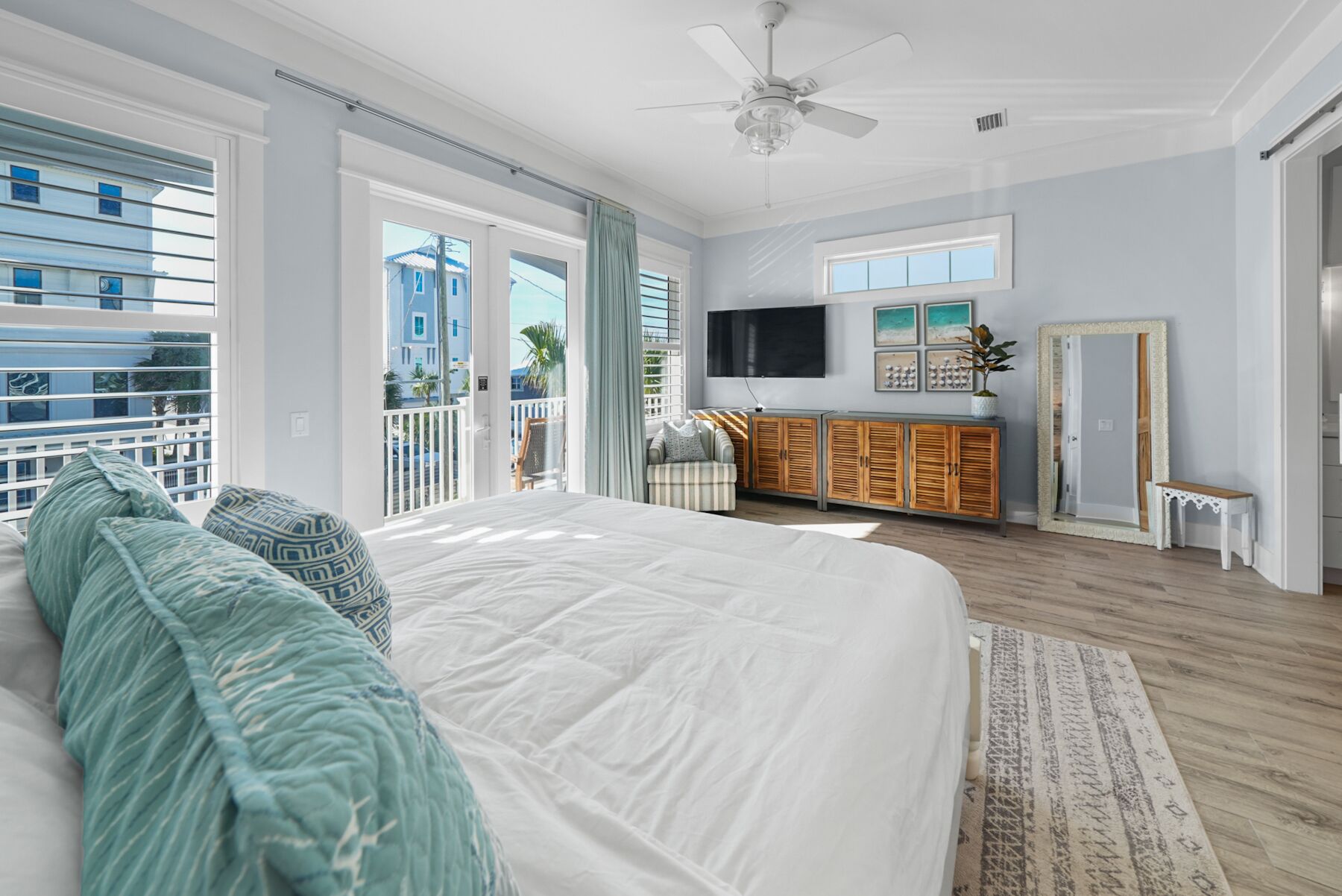 A spacious bedroom with a large bed, a ceiling fan, and a view of the outside balcony.