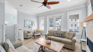 Un salon spacieux comprenant un canapé, des fauteuils, une table basse et un ventilateur de plafond.