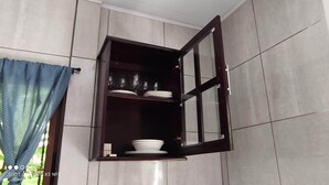 Un pensile d'angolo con cornice scura, contenente piatti e ciotole impilati.