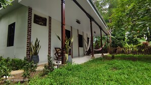 Una casa con portico coperto, piante in vaso e un'amaca.