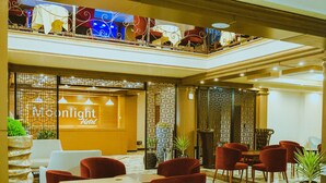Una hall d'albergo con reception, area salotto e elementi decorativi.