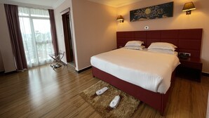 Camera d'albergo con un grande letto, due lampade ai comodini, un quadro appeso alla parete e vista dalla finestra.