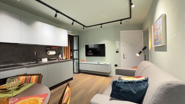 Um espaço de estar moderno com cozinha, sala de jantar e um sofá.