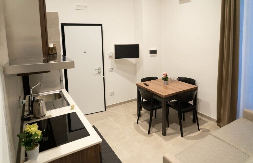 Une cuisine compacte comprenant un évier, une cuisinière et une petite table à manger avec des chaises.