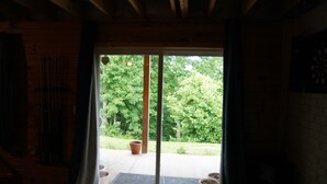 A room with a wooden interior, a sliding glass door leading to a garden with potted plants. - Honey Hole

 (Stockport)