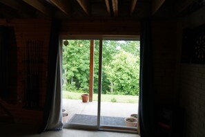 Una habitación con detalles de madera y un ventanal corredero que da a un jardín con macetas.