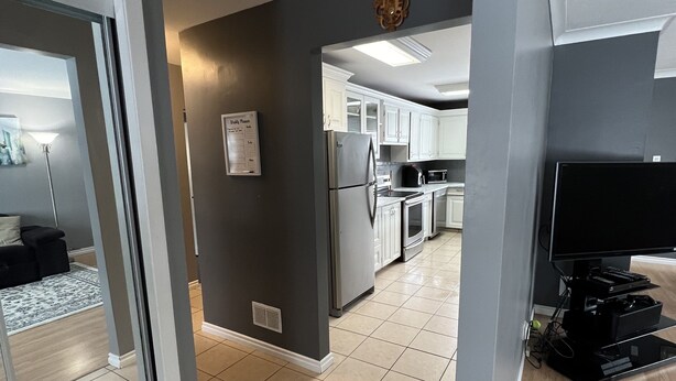 A modern kitchen with white cabinets, a refrigerator, and a microwave. - Your Home Away From Home (Brandon)