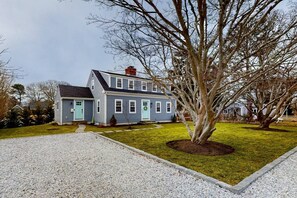 A two-story house with a front porch, a driveway, and a lawn. - Modern Cape Home in Hyannis walking distance to the beach & town! (Barnstable)