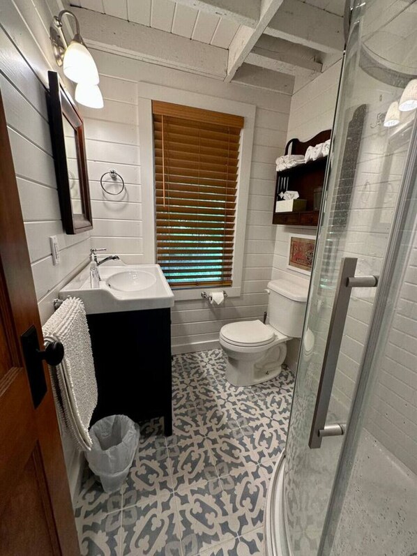 A bathroom with a white sink, toilet, and shower area.