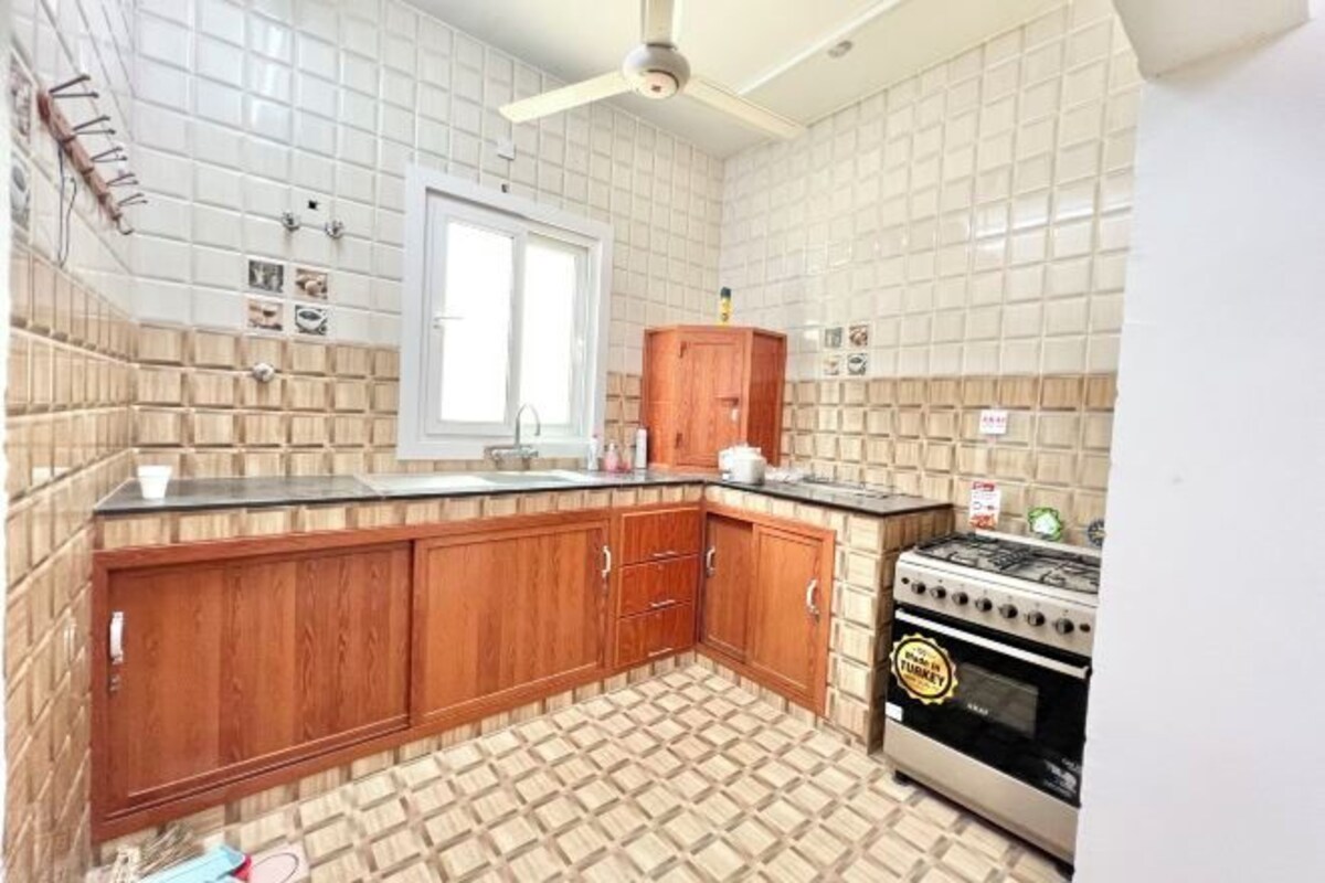 A kitchen with a tiled backsplash, wooden cabinets, a window, and a stove.