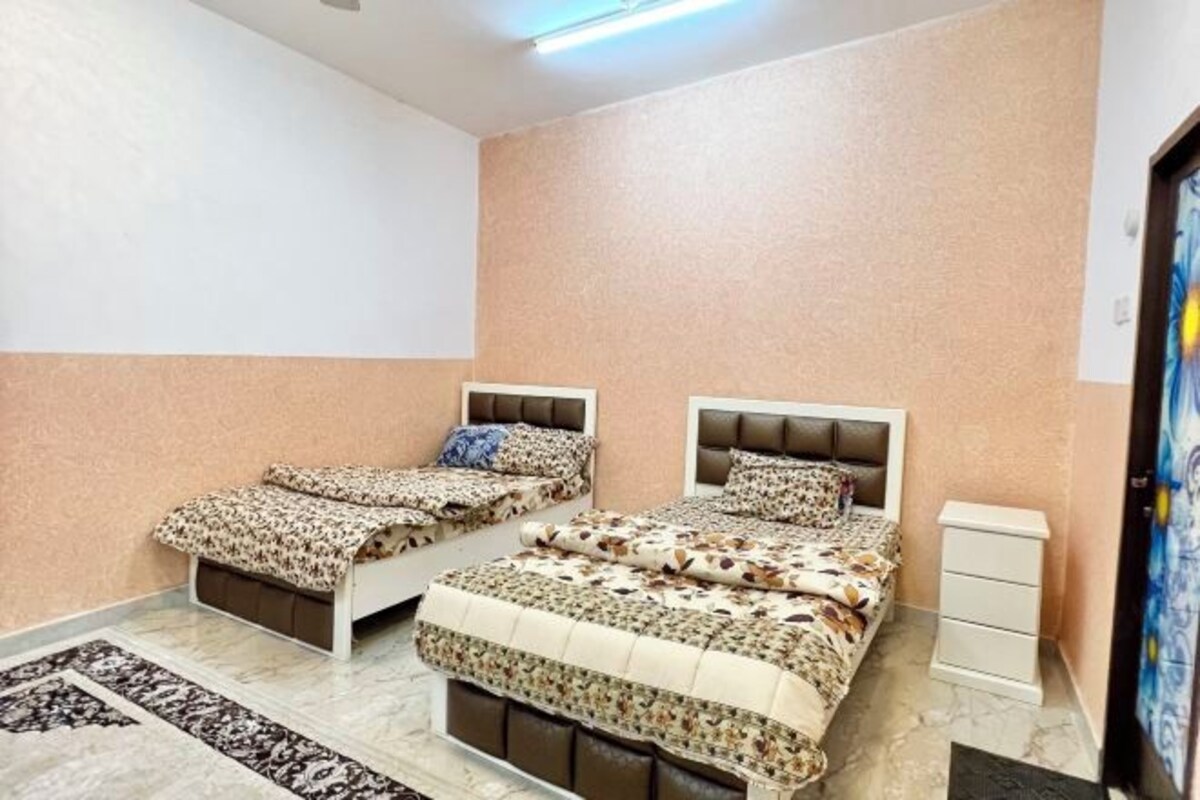 A bedroom with two beds, a nightstand, and a wall-mounted TV.