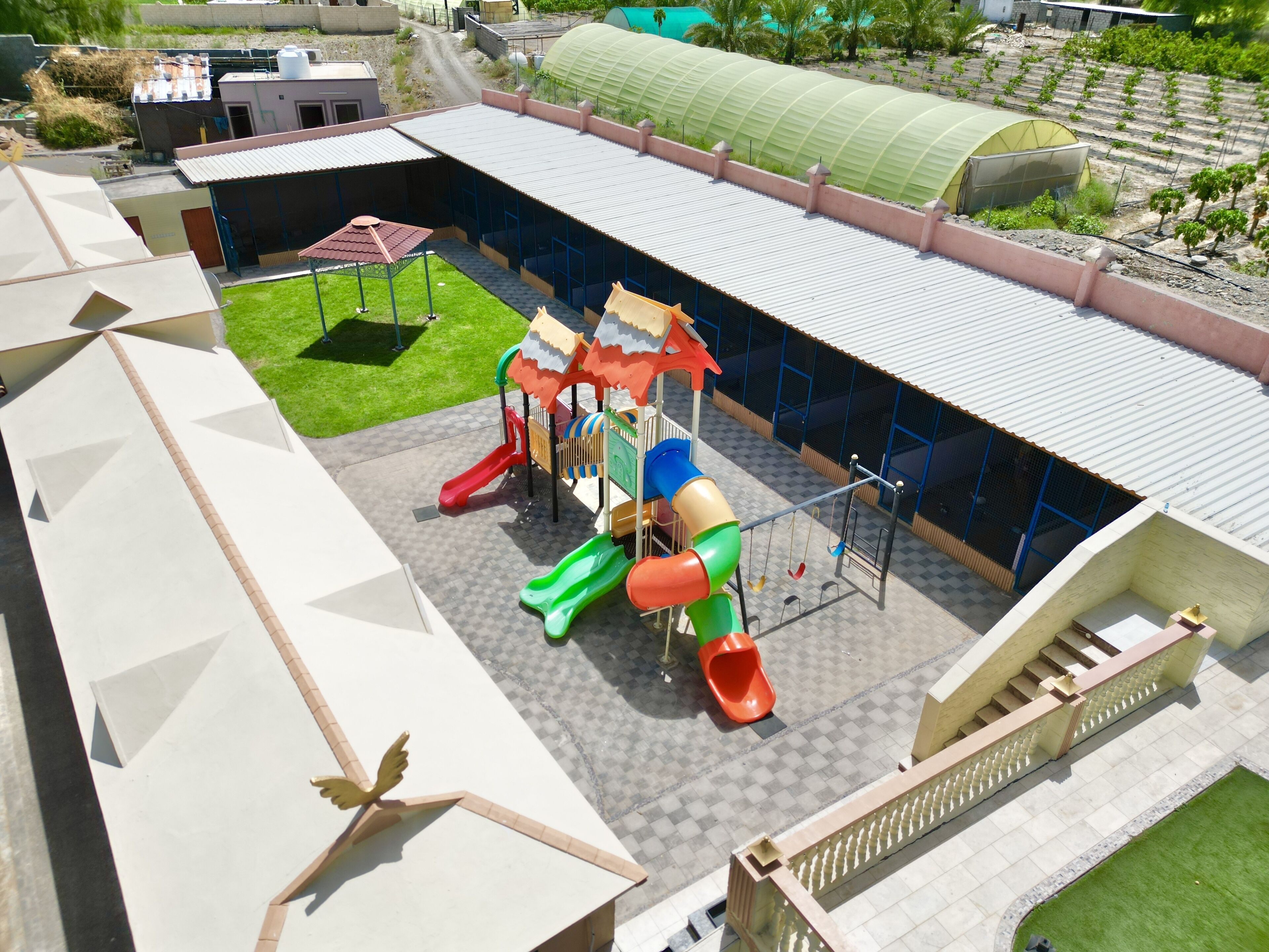 A playground with slides and swings, surrounded by buildings and a green area.