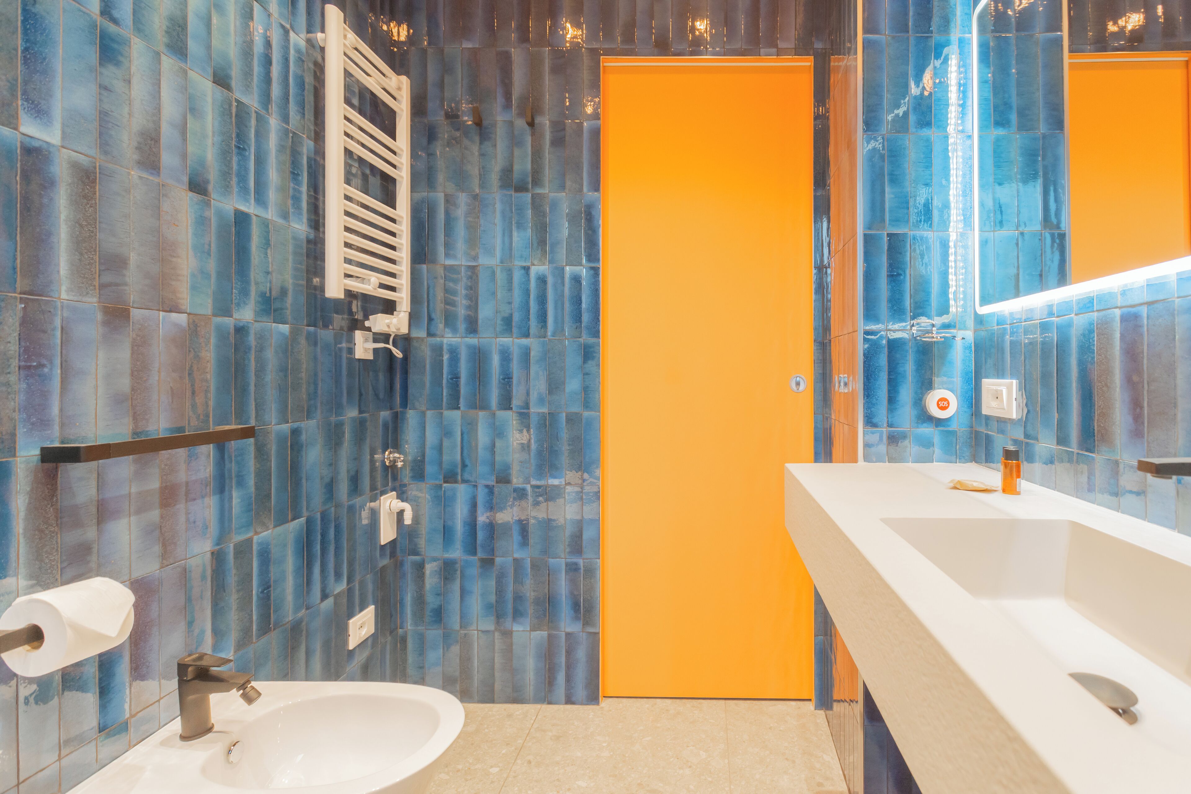 Un baño con un lavabo blanco, un espejo y un perchero para toallas.