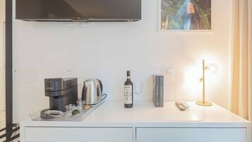 Eine moderne Küche mit Kaffeemaschine, einer Weinflasche und einer Fernbedienung auf der Arbeitsfläche.