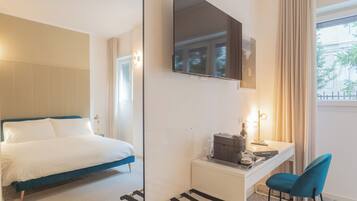 Una habitación de hotel con una cama, un escritorio con silla, un espejo y una ventana con cortinas.