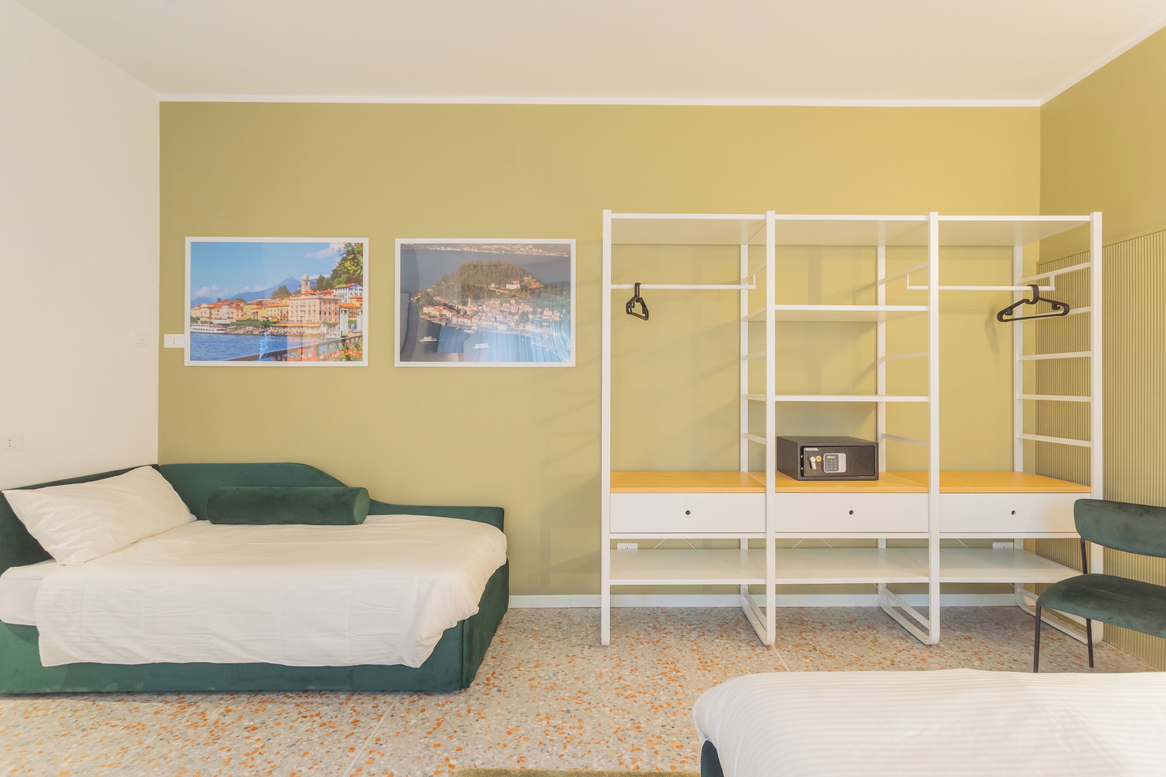 Ein Schlafzimmer mit einem Bett, einem Schreibtisch mit Stuhl und zwei Bildern an der Wand.