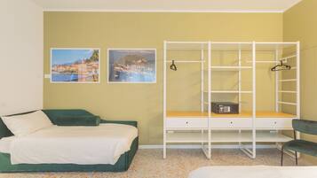 Ein Schlafzimmer mit einem Bett, einem Schreibtisch mit Stuhl und zwei Bildern an der Wand.