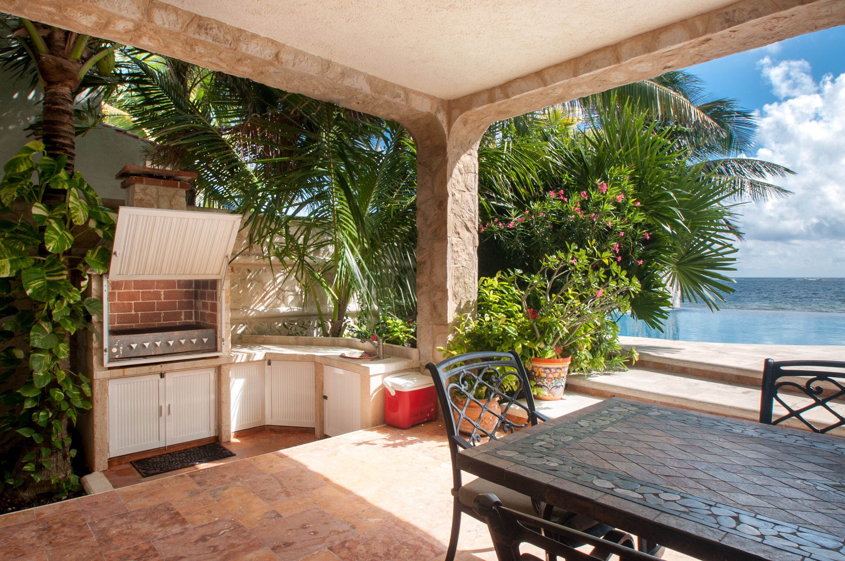 Une terrasse extérieure équipée d’un barbecue, d’un espace salon et offrant une vue sur l’océan.