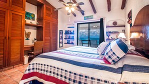 A bedroom with a large bed, wooden cabinets, a ceiling fan, and a view of the ocean. - Casa Del Sol: Beachfront Villa, Infinity Pool, 7 bedrooms, Made for Big Groups (Puerto Morelos)