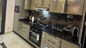 A kitchen with stainless steel appliances, a black countertop, and beige cabinetry.