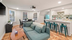 Une cuisine moderne avec des meubles blancs, un îlot de couleur bleue et des tabourets de bar turquoise.