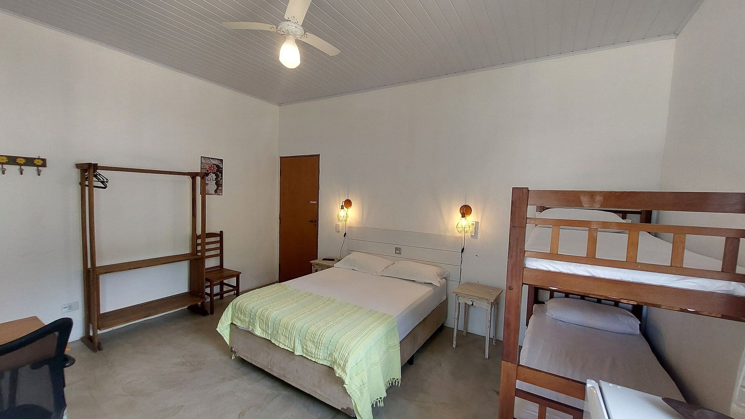 A bedroom with a bed, a wooden bunk bed, a desk, and a chair.