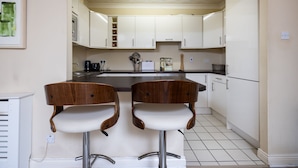 A kitchen with two wooden bar stools, white cabinets, a microwave, and a coffee maker. - Fantastic 2BD apt in THE best location in Dublin (Dublin)