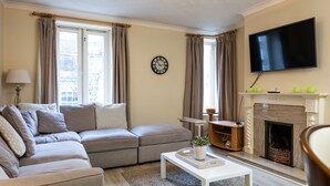 A living room with a sofa, a coffee table, a fireplace, a TV, and a clock on the wall. - Fantastic 2BD apt in THE best location in Dublin (Dublin)