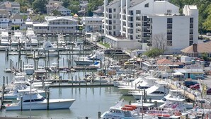 Un port de plaisance où sont amarrés de nombreux bateaux, entouré d’immeubles résidentiels et d’un grand bâtiment blanc doté de nombreuses fenêtres.