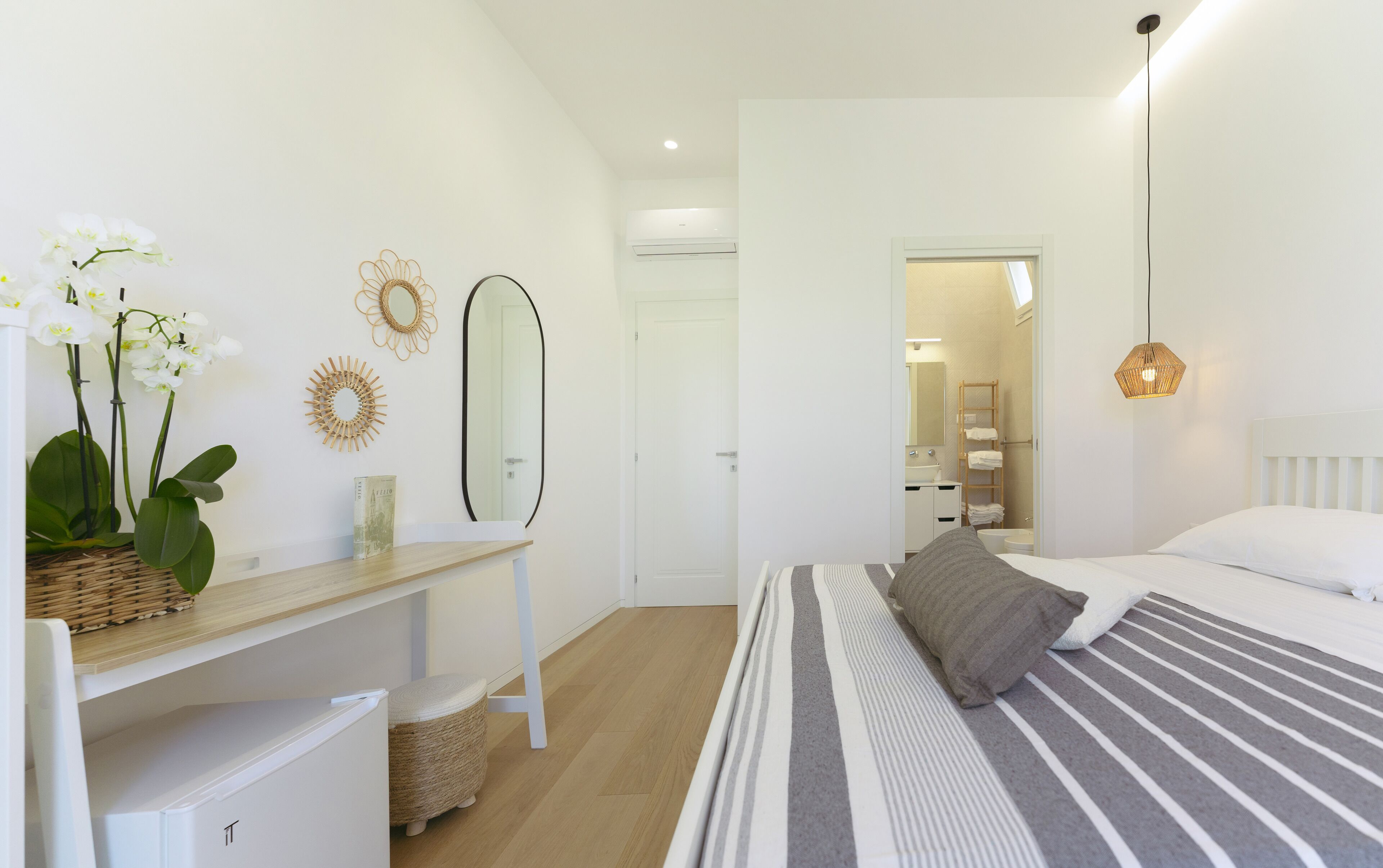 A bedroom with a bed, bedside table, and a desk with a mirror.