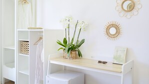 A white room with a wooden shelf holding a plant and a book, a white wardrobe, and a mirror on the wall. - Sea More - Rooms (Procida)
