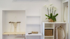 A white room with a shelf holding a woven basket, a macrame piece, and a pair of sunglasses. - Sea More - Rooms (Procida)