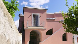 A pink building with a balcony and arched windows. - Sea More - Rooms (Procida)