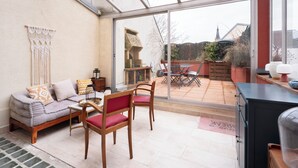 Une terrasse ensoleillée avec un canapé, des fauteuils et une table à manger.